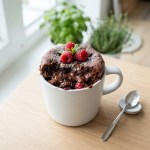 Schokoladen-Tassenkuchen in einer Tasse mit Schokostückchen und Puderzucker