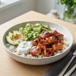 Lachs-Reis-Bowl mit Gurke, Avocado und Joghurt-Sauce, mit Sesam bestreut
